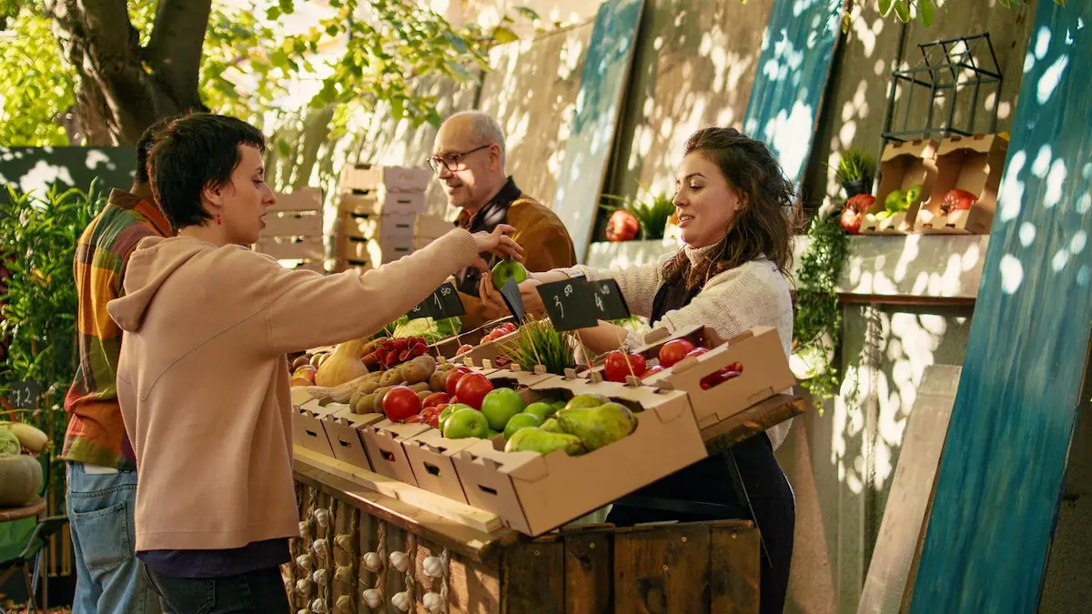 Woman buying fresh apples from a friendly vendor at an outdoor market stall