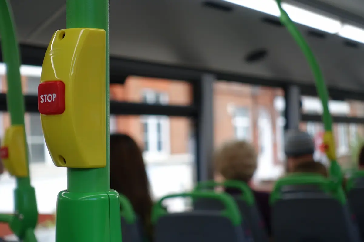 Close up of a red bus stop request button on a green pole