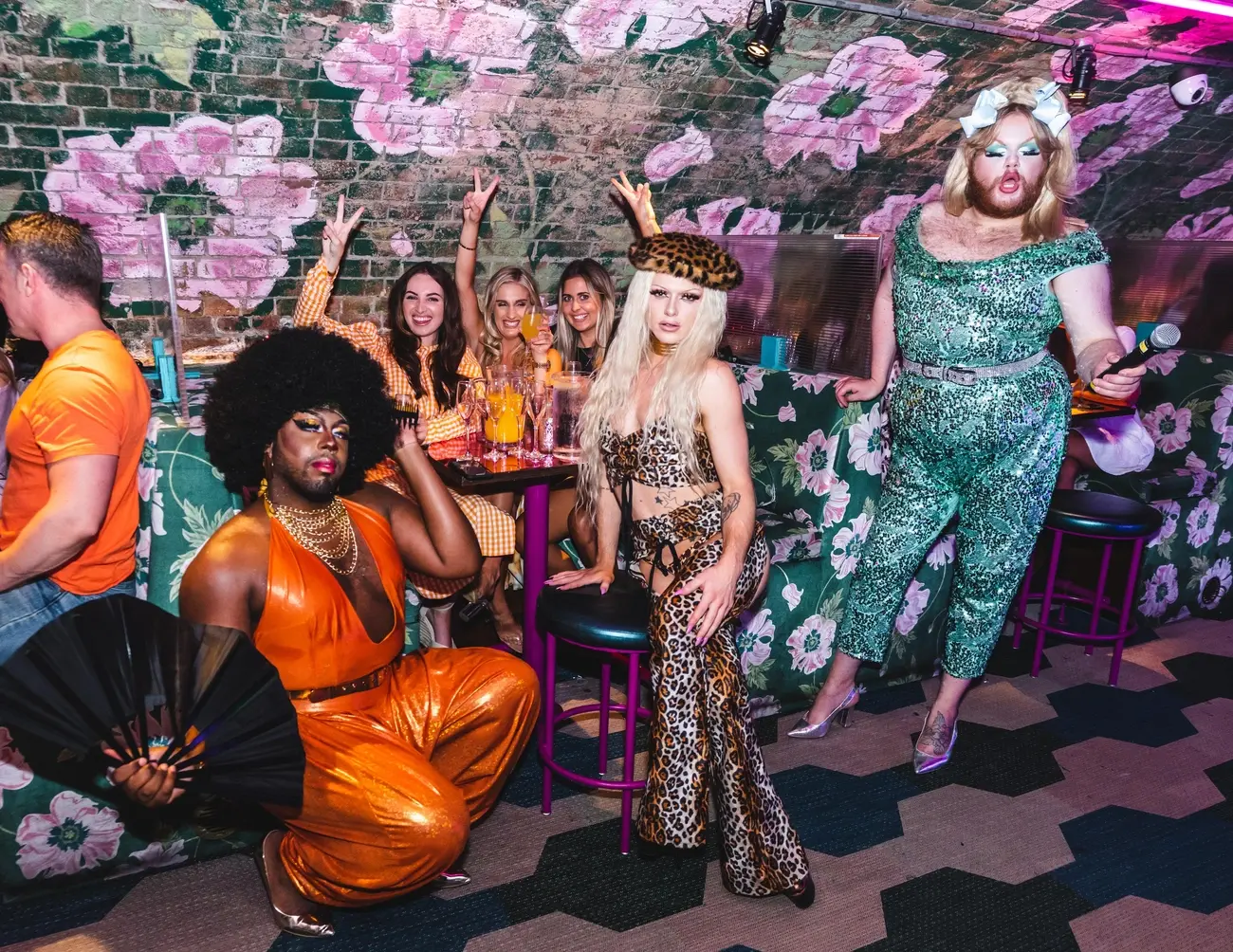 Drag queen in a vibrant outfit performing with a microphone at a Blame Gloria Bottomless Brunch London