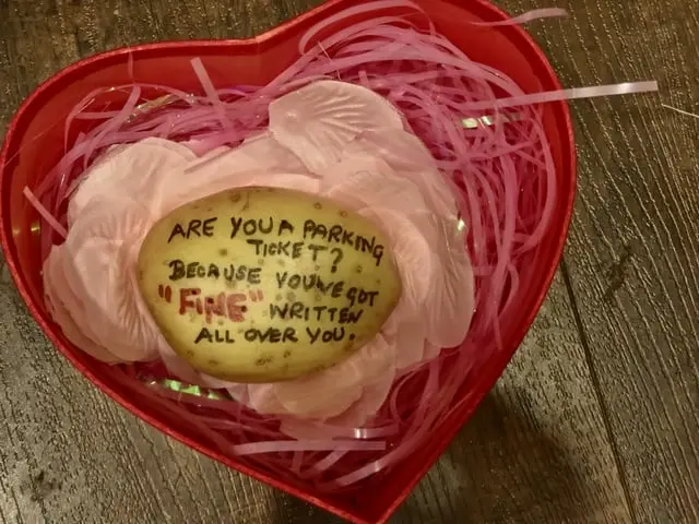 Potato in heart-shaped box with 'parking ticket fine' pick-up line written on it