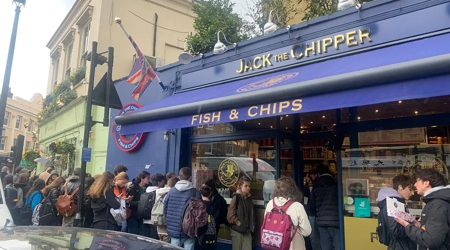 Queue of people outside the Jack The Chipper fish and chips shopfront in Greenwich