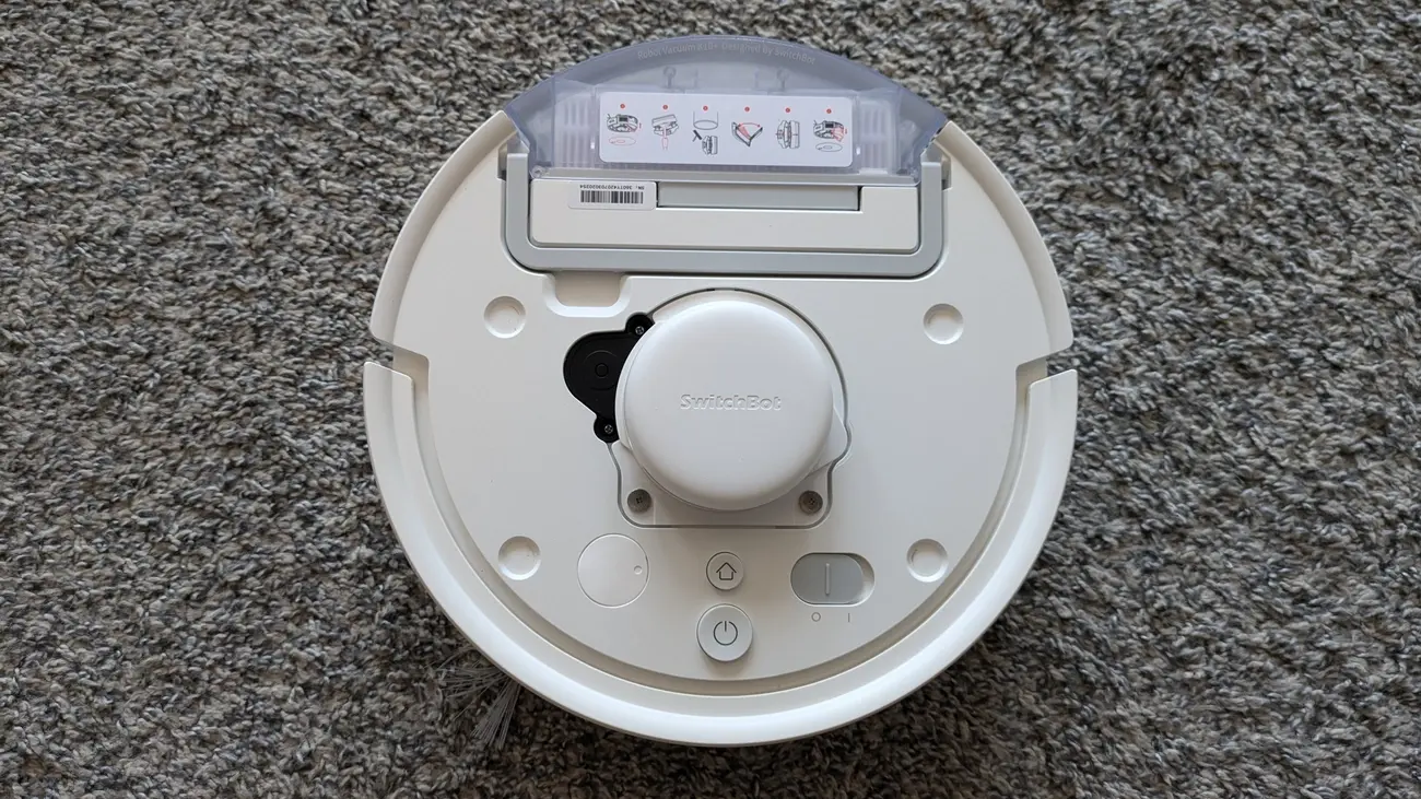 Underside view of the white SwitchBot K10+ mini Robot Vacuum on a grey carpet