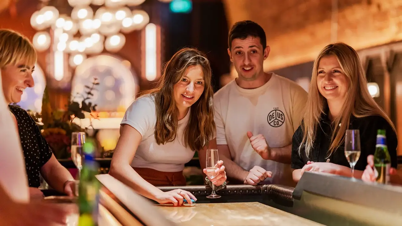 Group of friends playing shuffleboard and enjoying drinks at Electric Shuffle London Bridge brunch