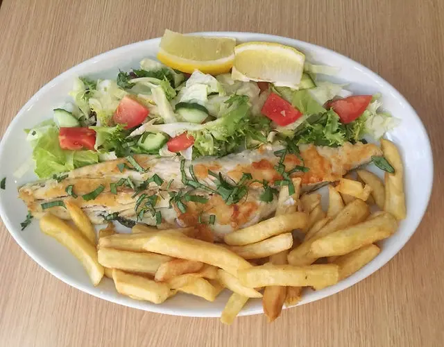 Plate of grilled fish served with chips and salad