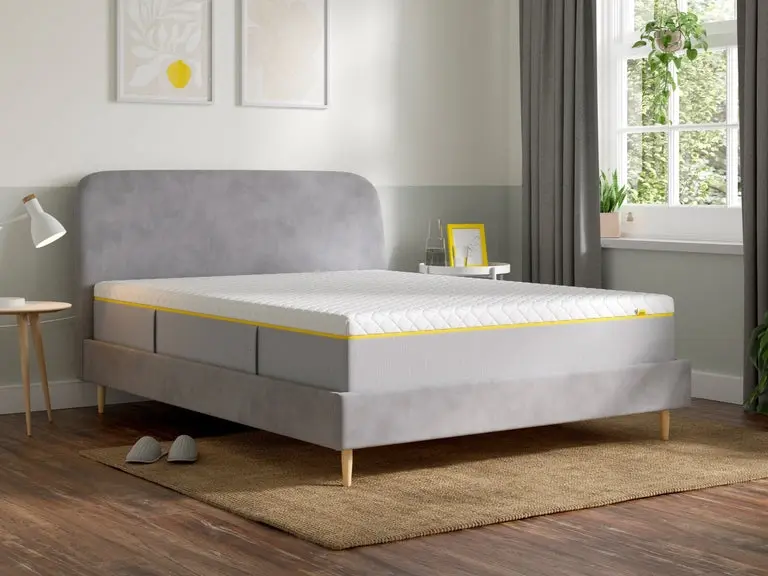 Eve Wunderflip mattress with yellow piping on a grey bed frame in a bedroom