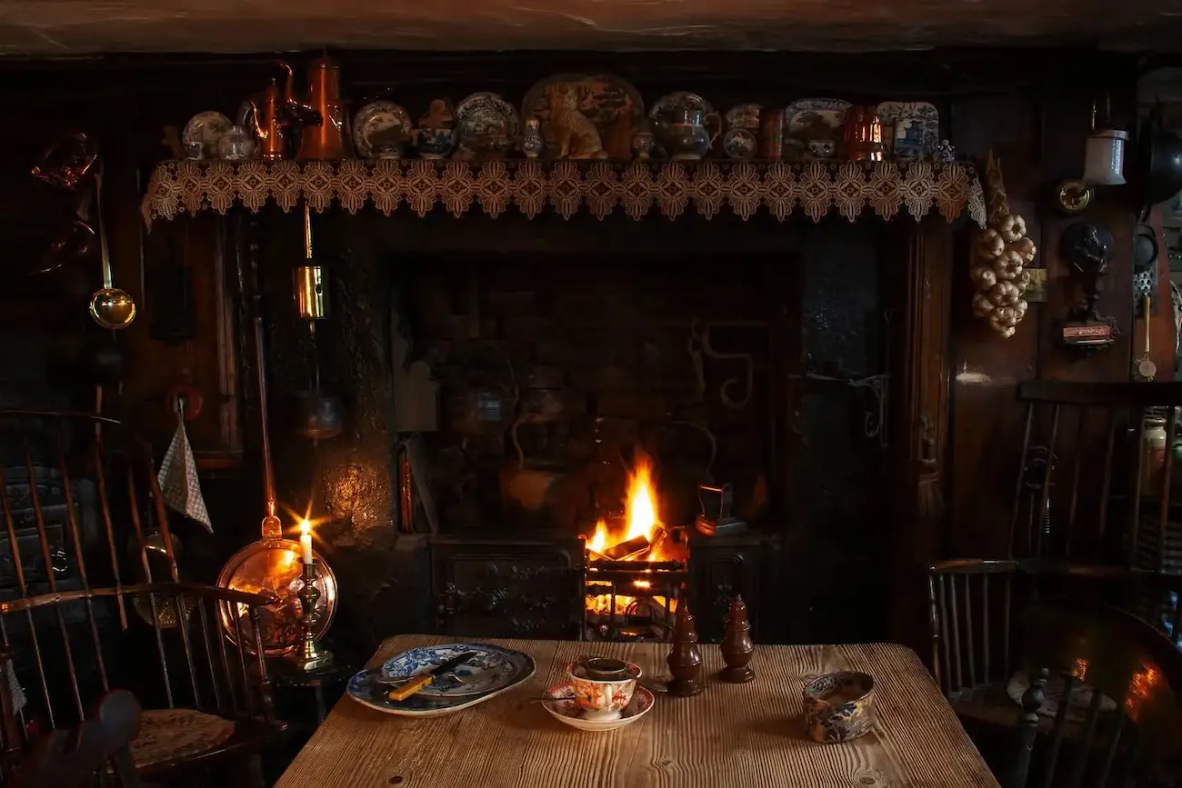 Atmospheric, candlelit room in Dennis Severs' House with a glowing fireplace and period table setting