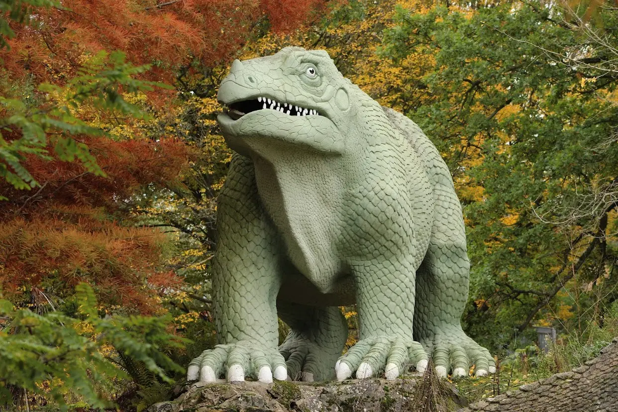 Victorian Iguanodon dinosaur statue amongst autumn trees in Crystal Palace Park, one of the unique Parks in London