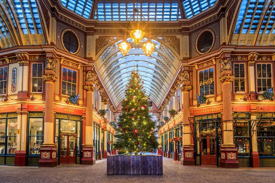 A large Christmas tree standing in the centre of the ornate Victorian Leadenhall Market, with its glass roof and festive shops