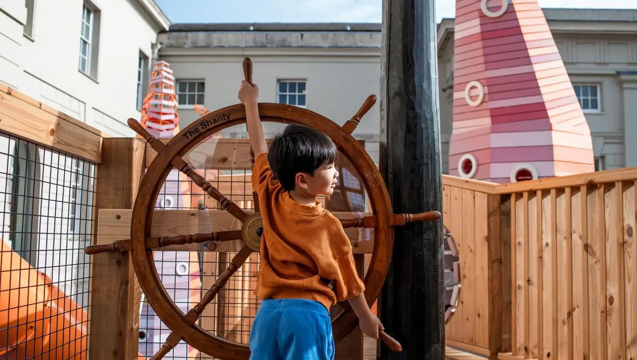 Boy at ship's wheel in The Cove playground, Maritime Museum; engaging Thing to Do in London with Kids