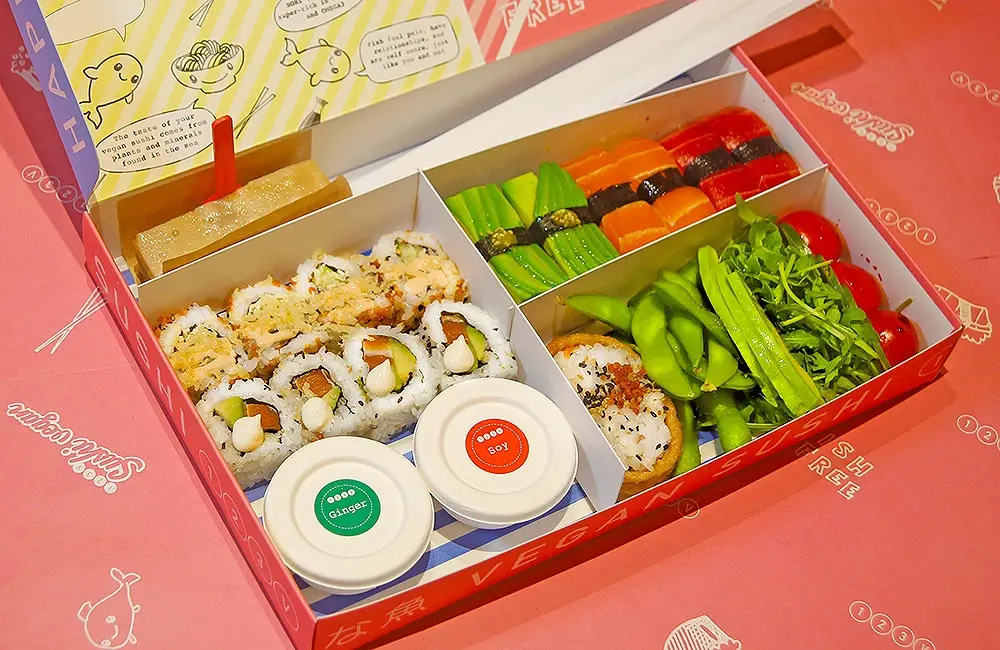 A bento box filled with a colourful selection of plant-based sushi, rolls, and edamame from 123 Vegan