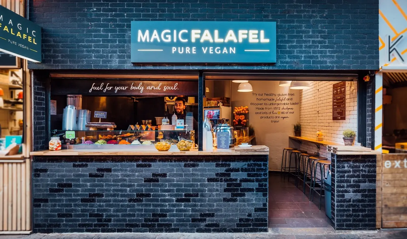 Magic Falafel Pure Vegan shopfront in Camden Market with service counter and stools