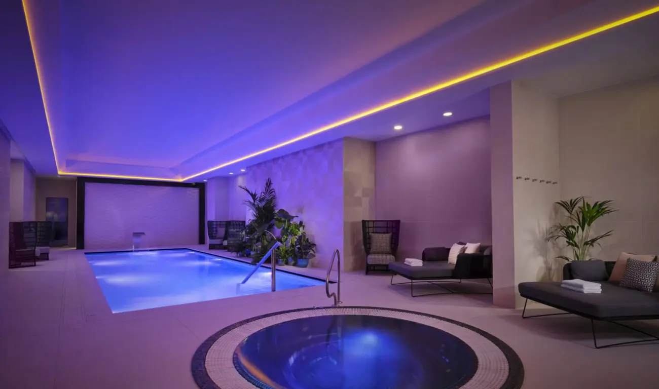 Serene indoor swimming pool area at Montcalm East hotel, with atmospheric lighting and loungers