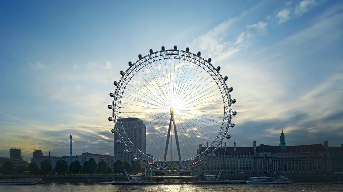 Sun bursts through the London Eye, silhouetted over the Thames. A popular Thing to Do in London with Kids