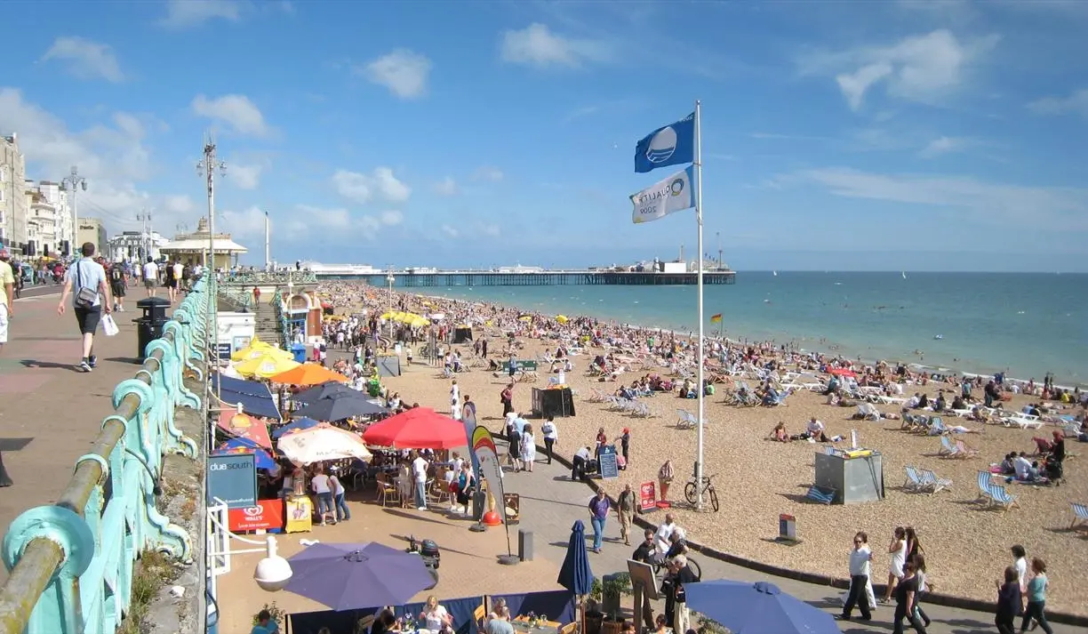 Crowded Brighton Beach on a sunny day viewed from the promenade, a popular spot for Things to Do in Brighton
