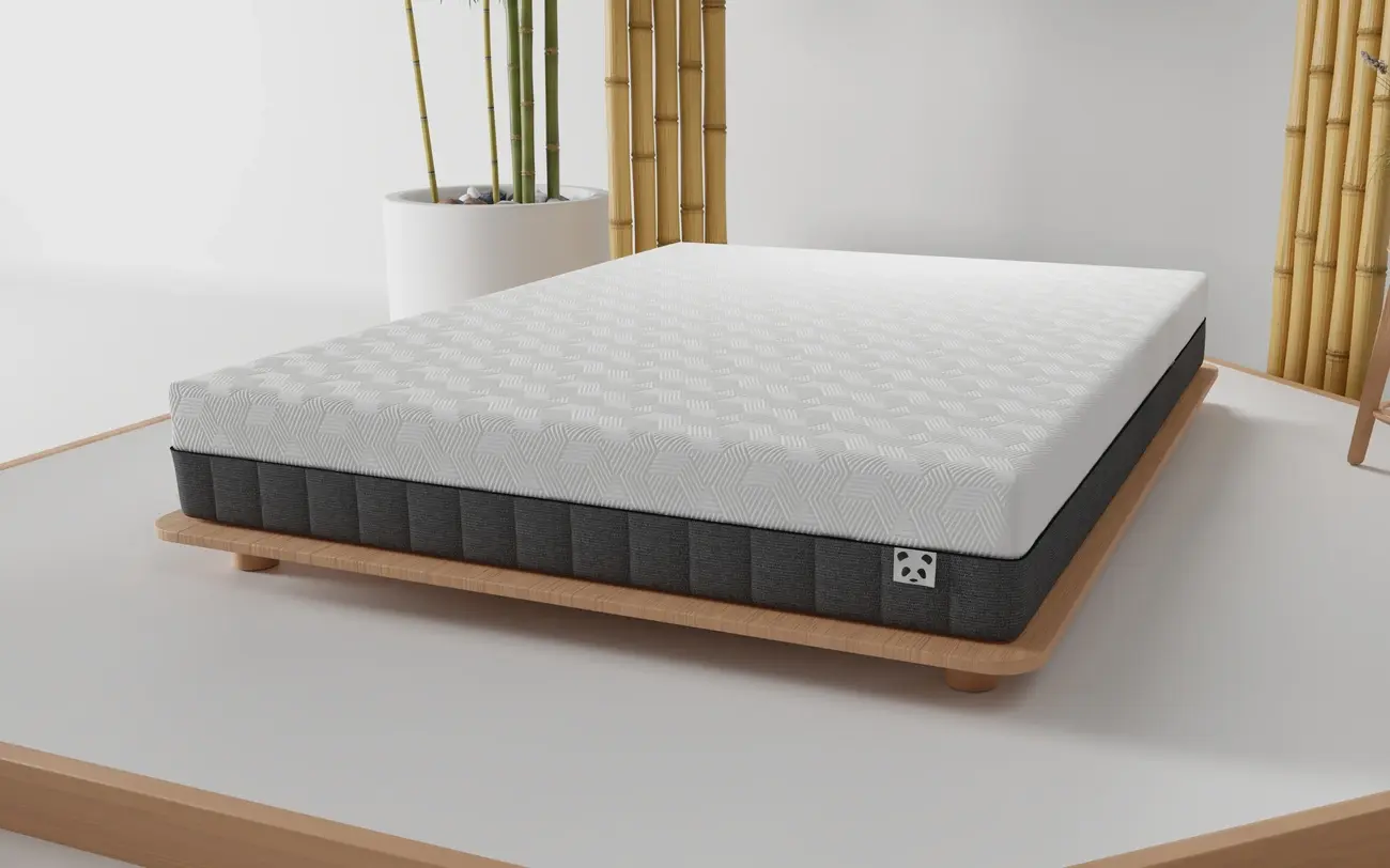 Panda Hybrid Bamboo mattress on a low wooden bed frame next to a bamboo plant