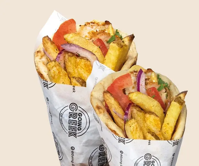 Two Going Greek gyros wraps filled with meat, chips, tomato, and red onion