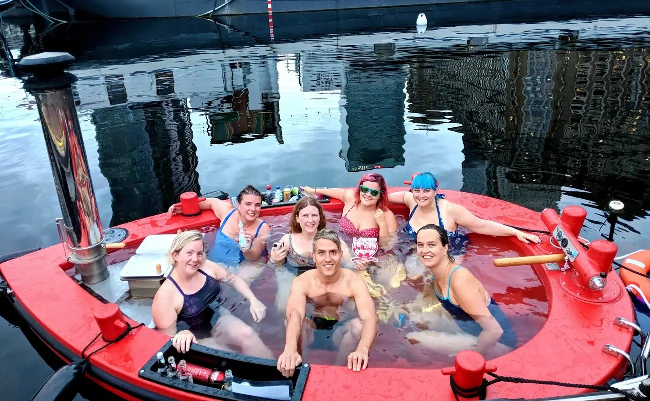 Group of people enjoying a Skuna Boats floating hot tub experience on the Thames in Canary Wharf