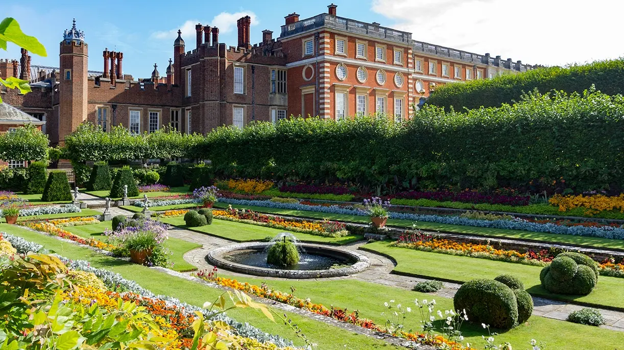 Formal gardens at Hampton Court Palace with colourful flowerbeds and a central fountain
