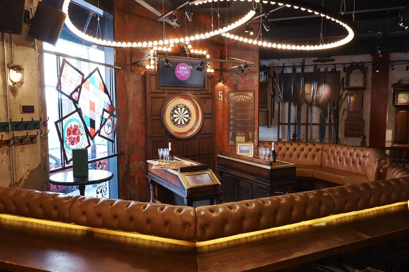 Friends playing social darts on an illuminated dartboard at Flight Club during a brunch event