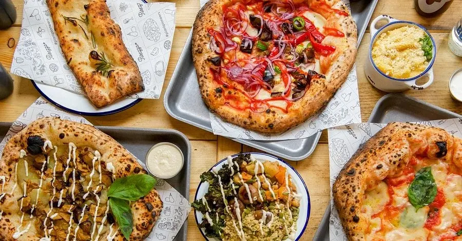 An overhead view of a table filled with various vegan sourdough pizzas and sides from the pizzeria Purezza