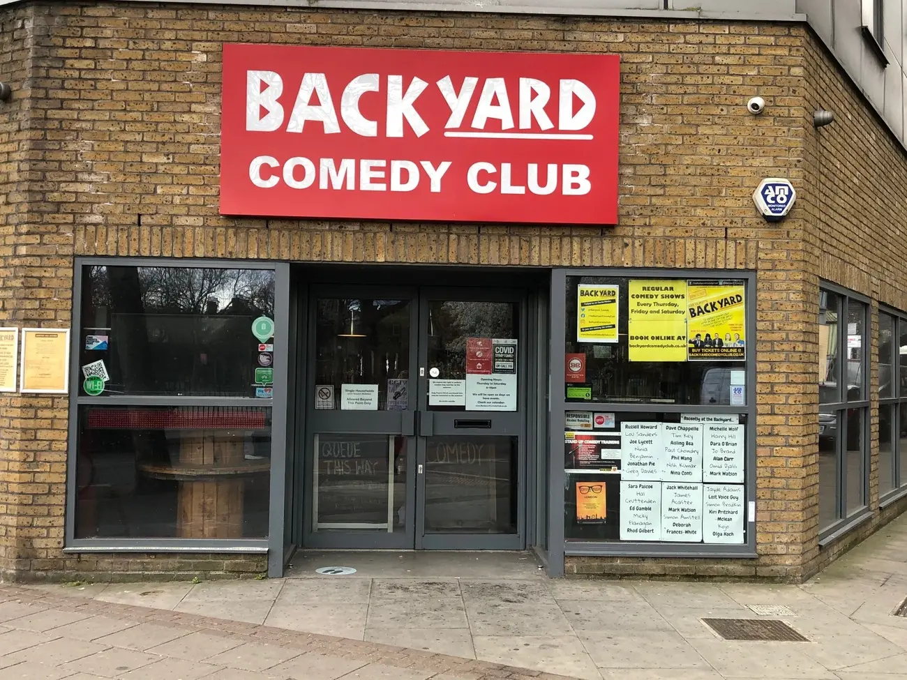Street-level view of the entrance to the Backyard Comedy Club in London, with its large red sign