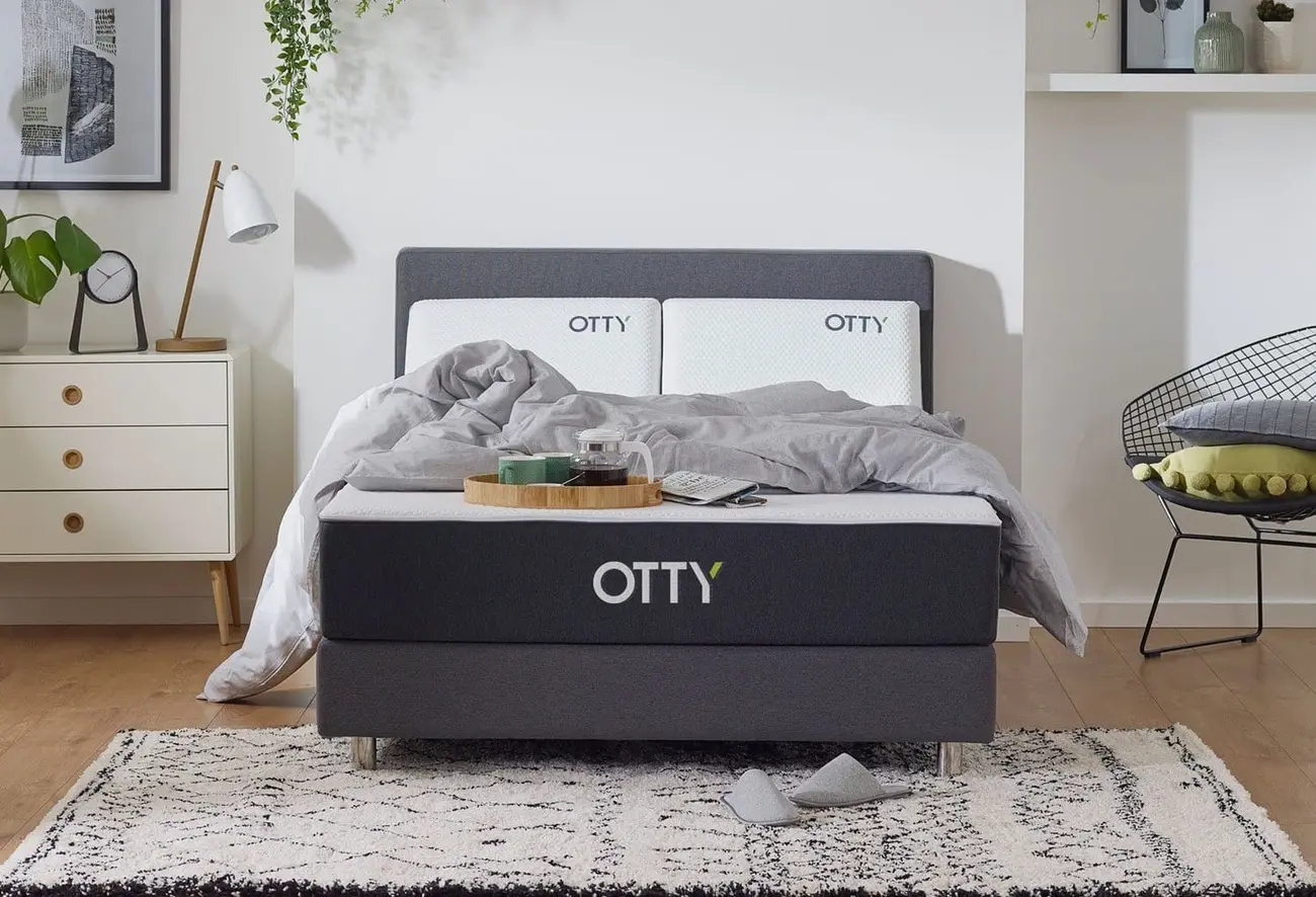 Otty Hybrid mattress on a bed base with grey bedding and breakfast tray