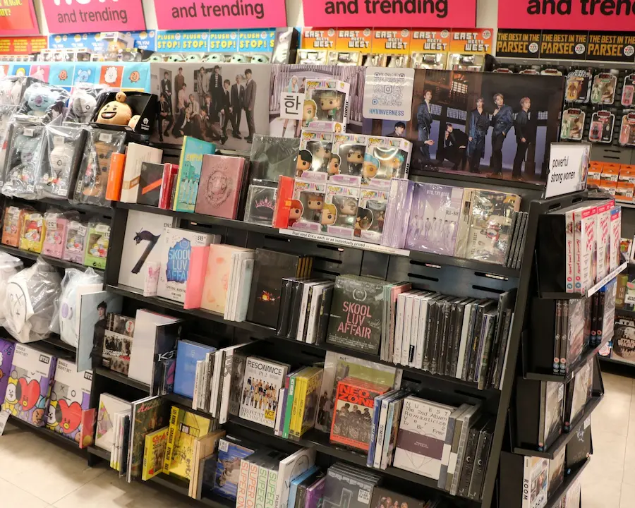 An in-store display at HMV showing shelves stocked with K-pop albums, Funko Pop figures, and other merchandise