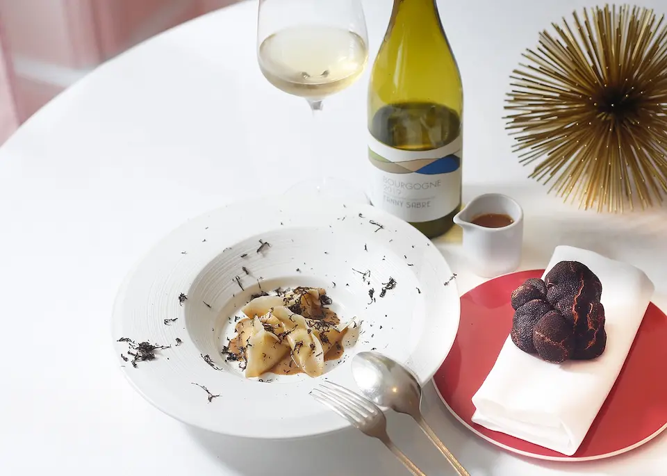 An elegant vegan truffle dish served with a glass of white wine at the fine-dining restaurant Gauthier Soho