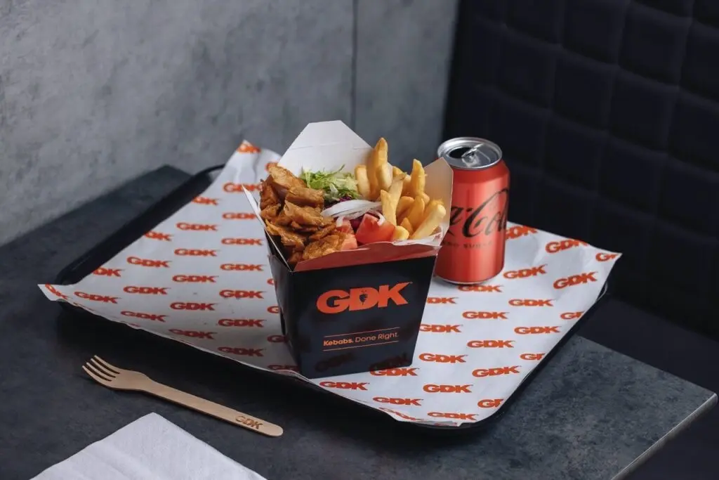 German Doner Kebab box filled with meat and chips next to a Coke can
