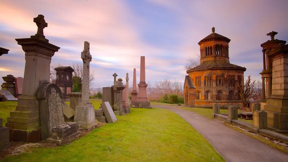Path winding through Glasgow Necropolis with various Victorian monuments, gravestones, and a large circular stone building
