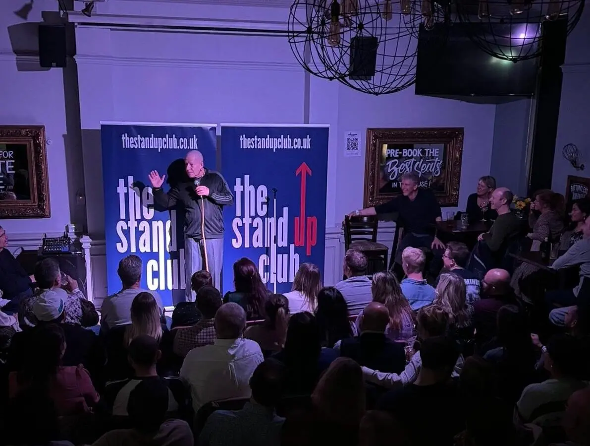 Comedian performing live stand-up on stage for an audience at The Stand Up Club in London