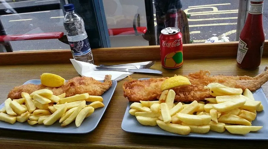 Two plates of traditional fish and chips with lemon wedges at Baileys