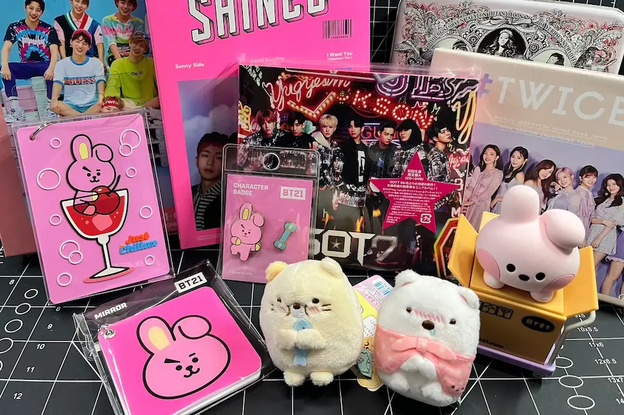 An assortment of colourful K-pop merchandise, including albums, BT21 character goods, and cute plush toys