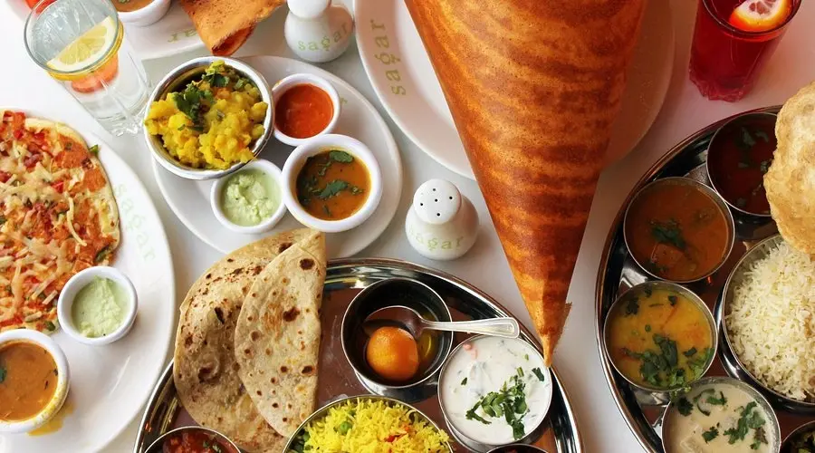 A colourful table spread of South Indian dishes, including a large dosa and a thali, at Sagar restaurant