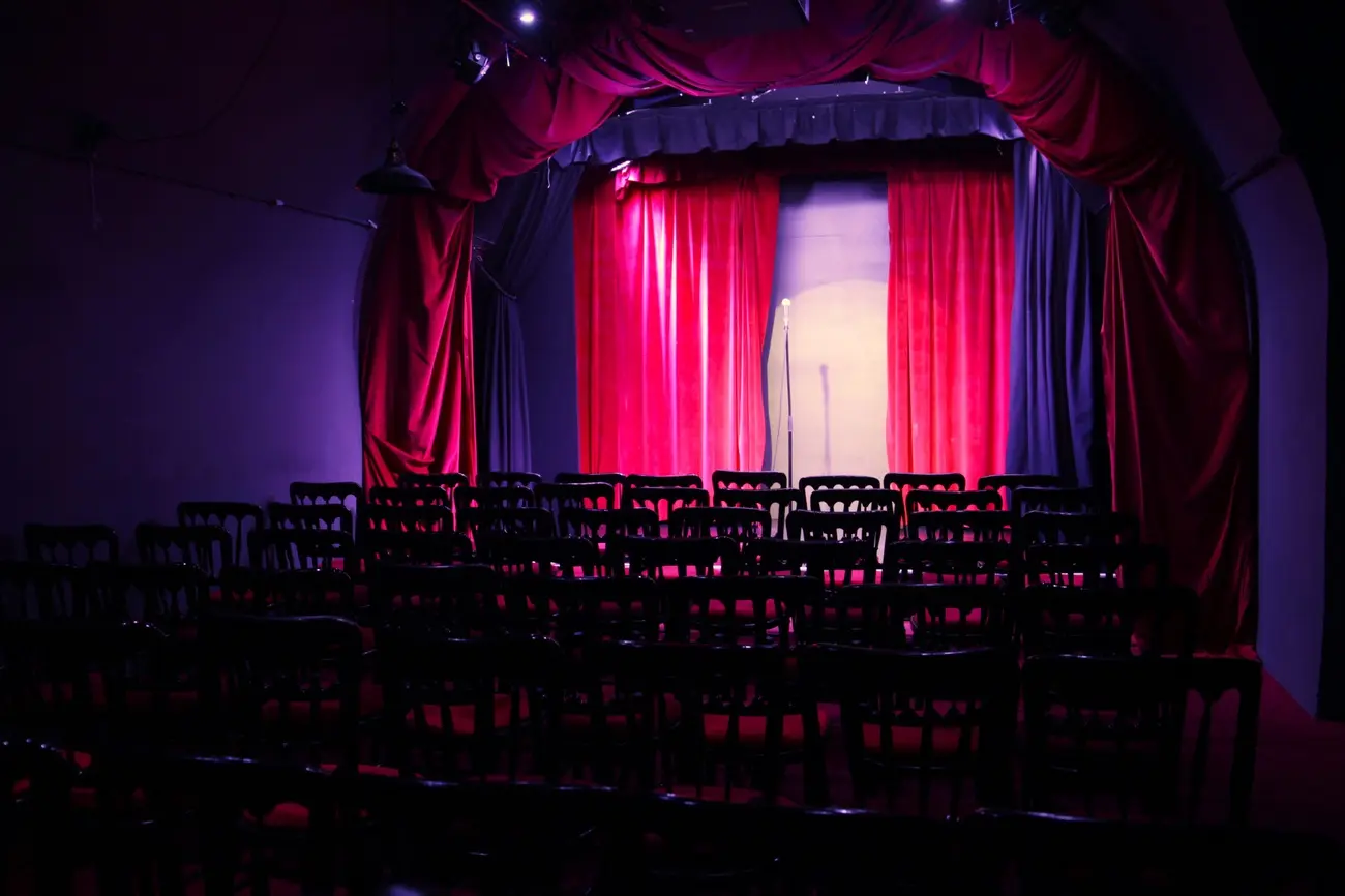 Empty seats facing the small stage with red curtains at the Museum of Comedy in Bloomsbury