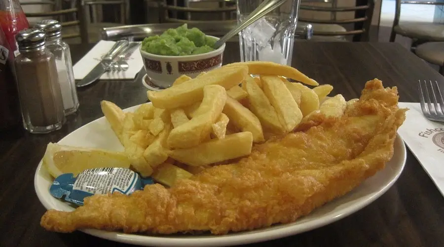 Plate of classic fish and chips served with mushy peas and lemon