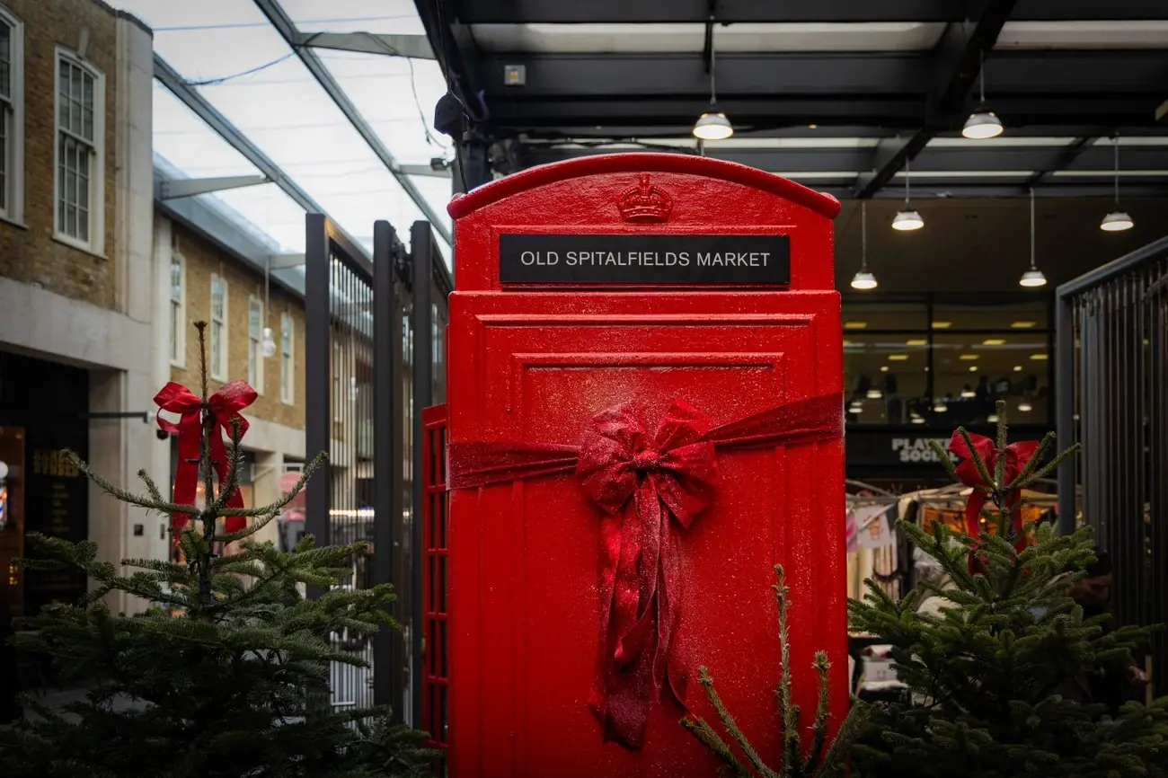 A classic red postbox for Old Spitalfields Market decorated with a large, glittery red bow for the Christmas season